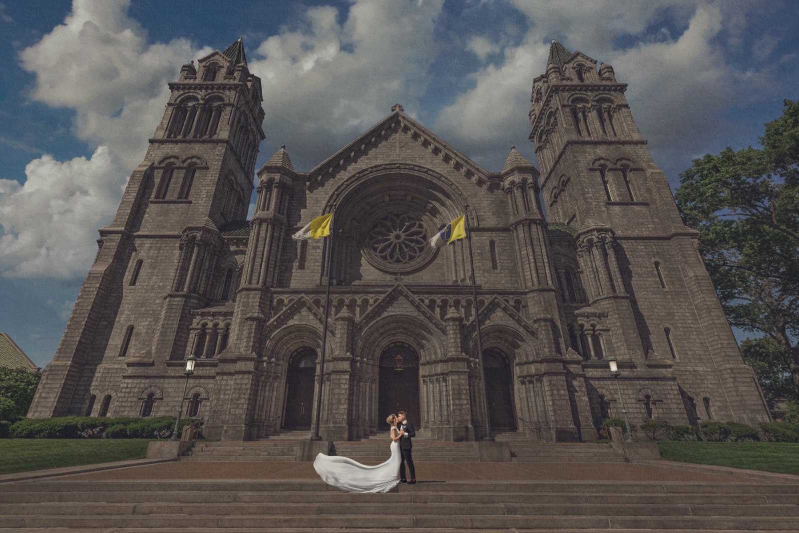 Bride and groom on the steps of the Cathedral Basilica of St. Louis beneath a blue sky