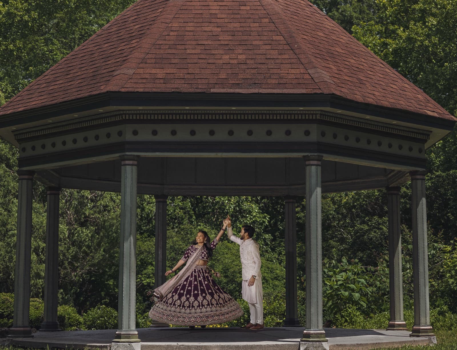 Couple twirling in formal attire inside a garden gazebo in St. Louis
