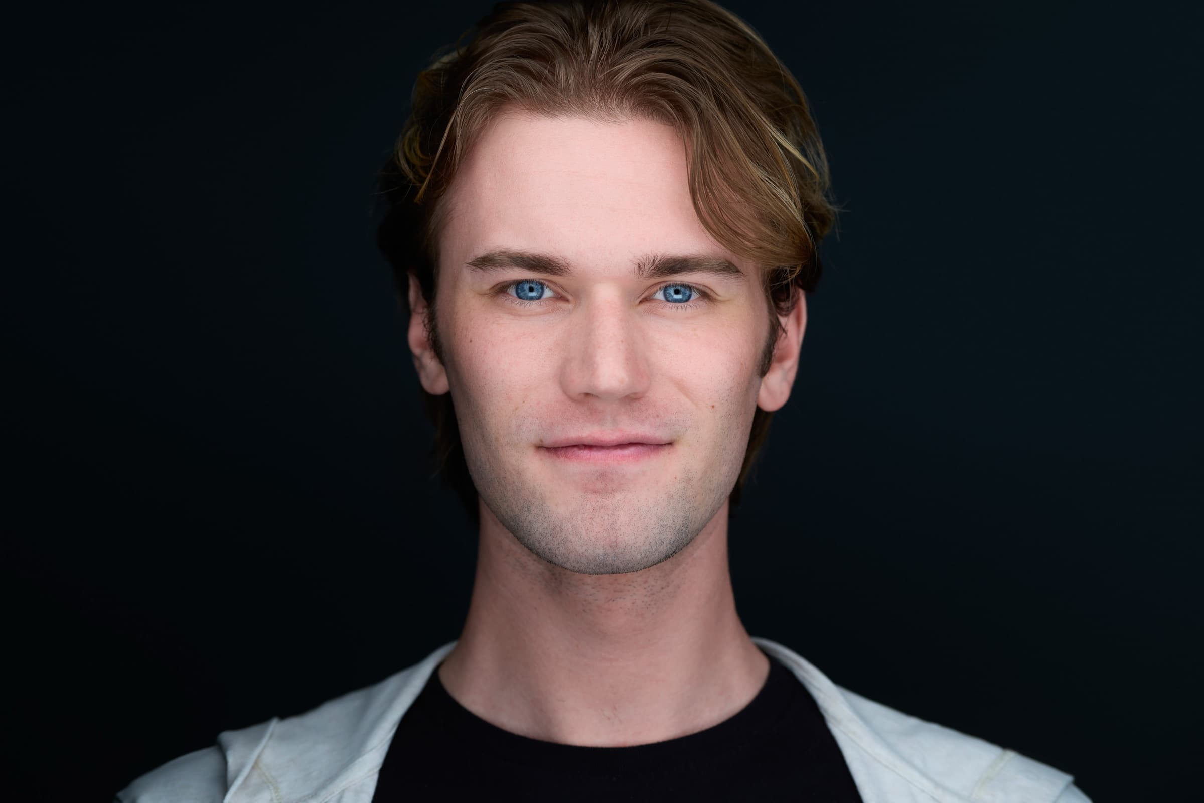 Professional headshot of a young man with blue eyes on a dark background in St. Louis by Zach Dalin