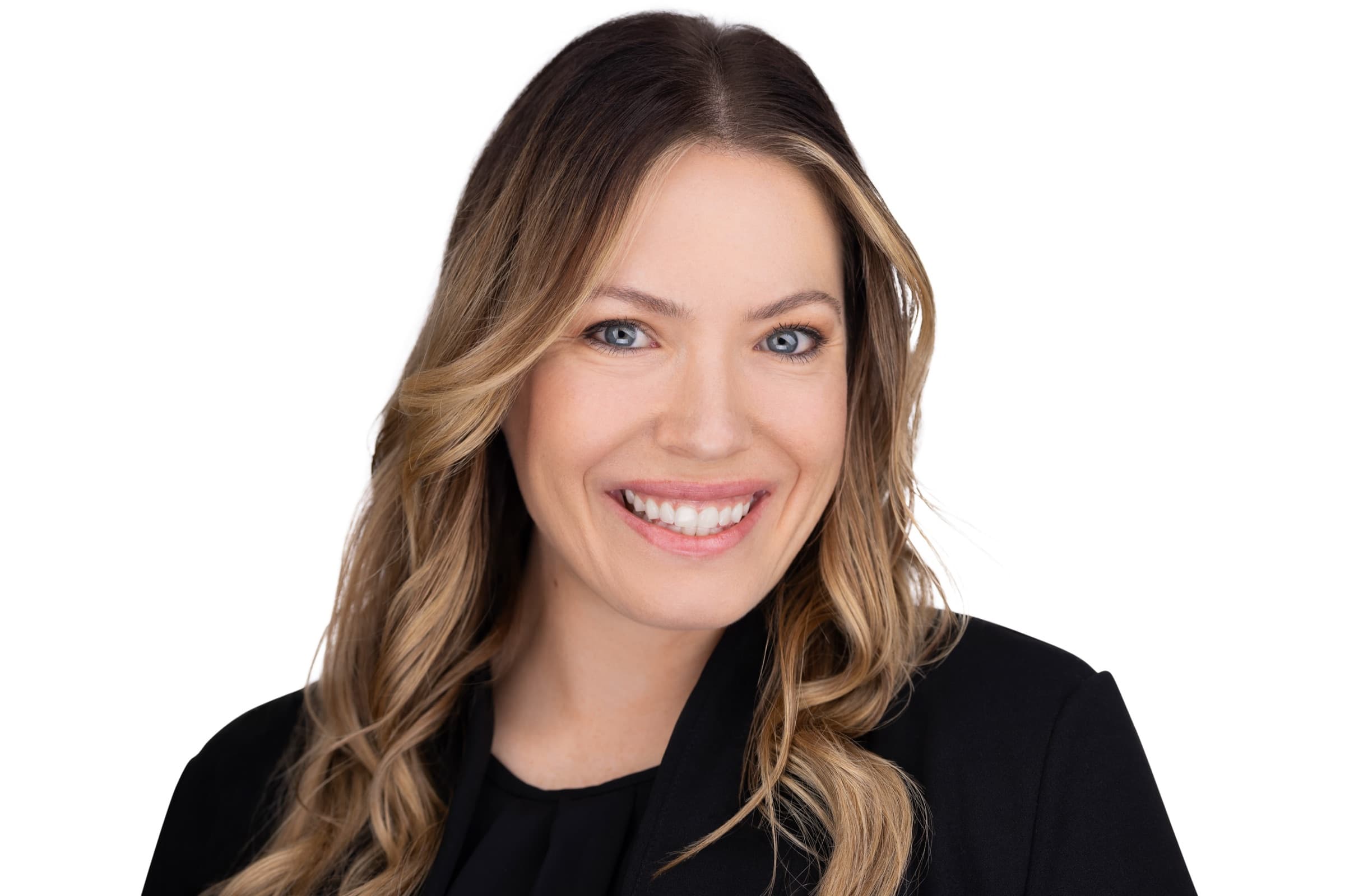 Executive headshot of a smiling woman with long wavy blonde hair in a black blazer on a bright white background by a St. Louis headshot photographer