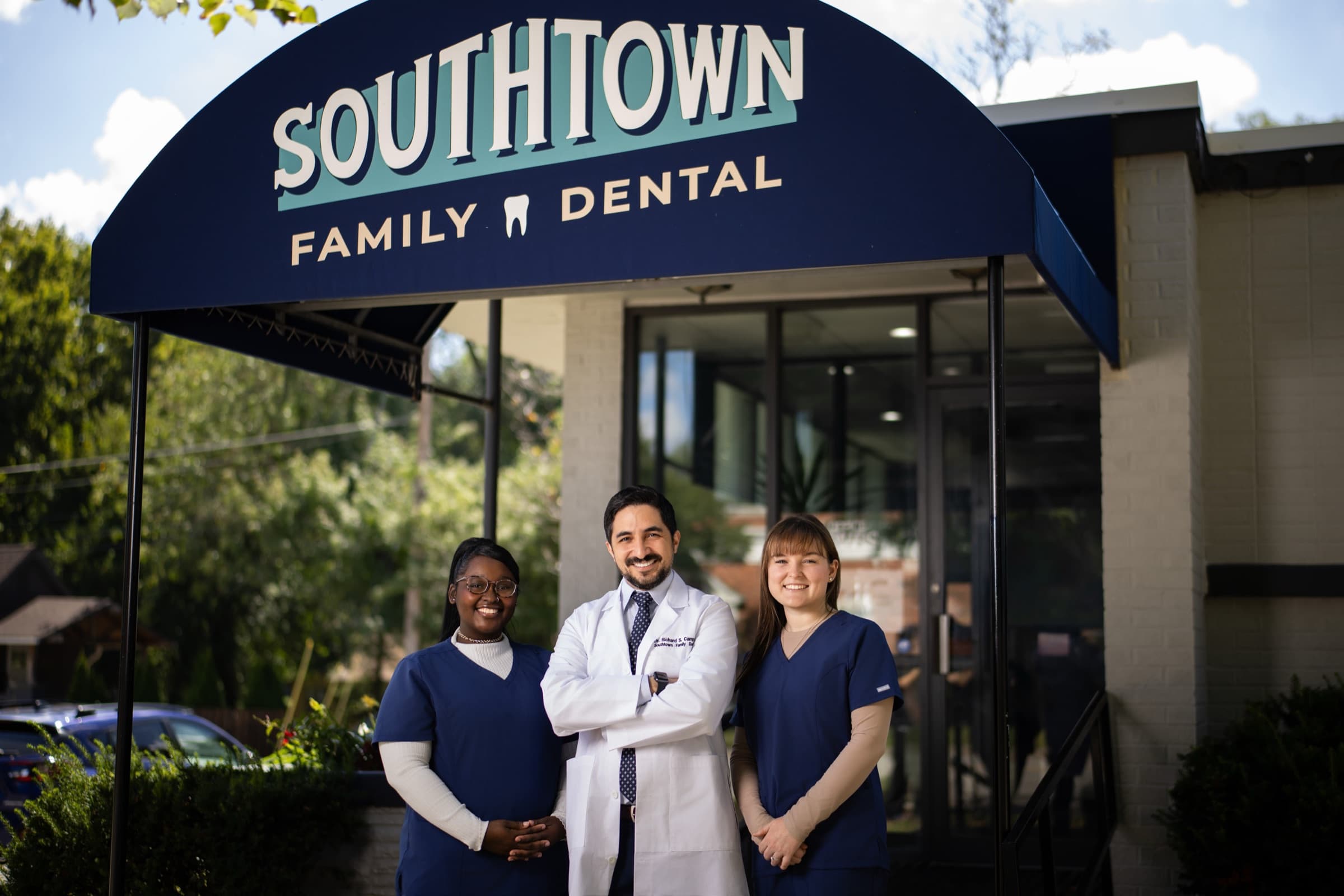 Three dental professionals standing beneath the Southtown Family Dental entrance sign at their St. Louis practice