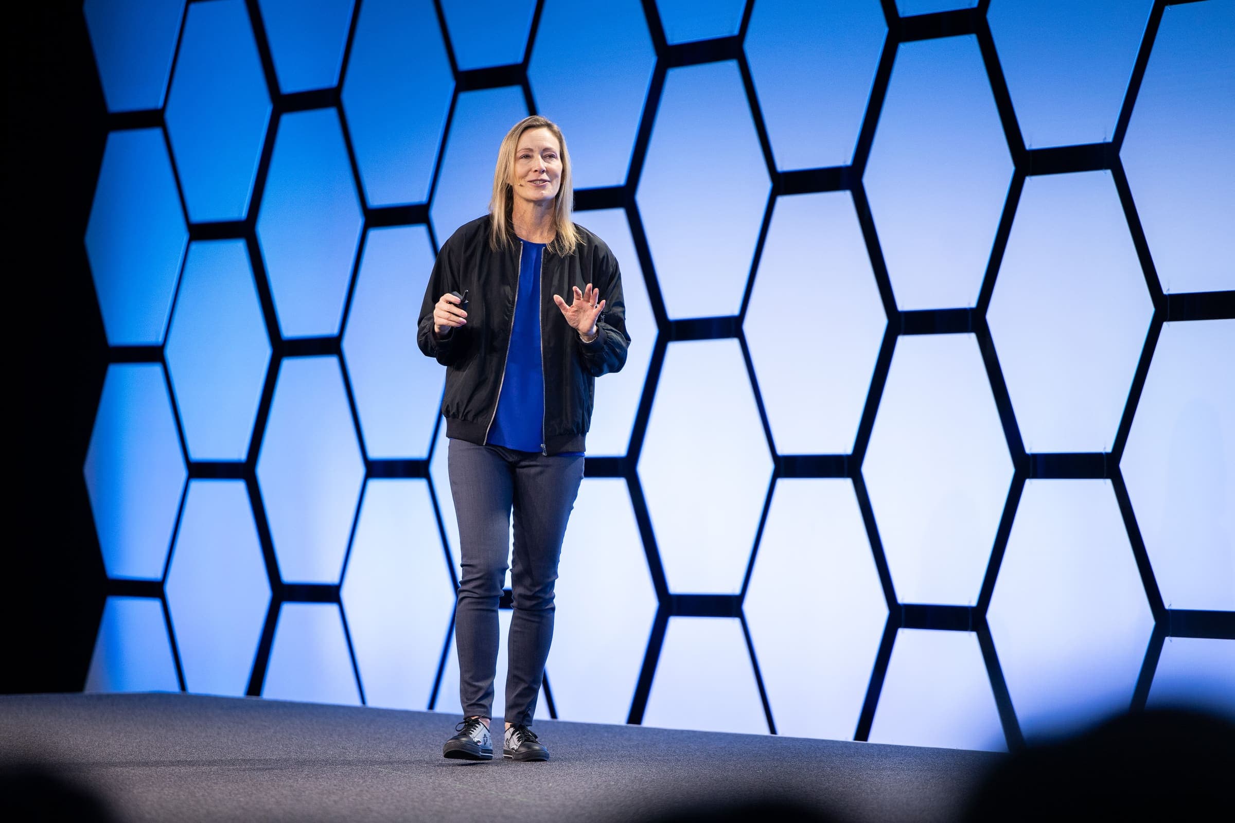 Keynote speaker on a blue hexagon-lit stage at a corporate event photographed by Zach Dalin Photography
